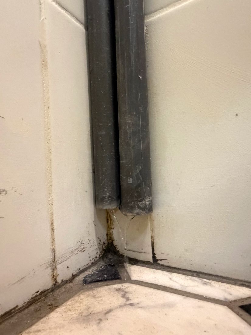 Two condensate drain lines discharging cleanly at a floor trap